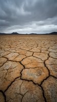 Cracked, parched earth stretches across an arid landscape beneath stormy skies, depicting severe drought conditions and environmental degradation for climate change awareness campaigns.