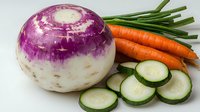 Fresh purple and white turnip with sliced cucumber and whole organic carrots on white background, raw vegetables for healthy cooking and salads.