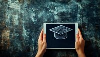 Hands holding small chalkboard with graduation cap sketch against dark textured background, representing education and academic achievement concept.