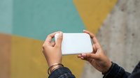 Hands holding blank white card against colorful geometric wall background. Mockup for branding, marketing materials, business cards, or promotional designs.