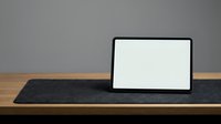 Laptop with blank white screen on wooden desk with dark mat, gray background, mockup for web design and business presentations.