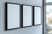 Three empty black picture frames hanging on white wall near window with natural daylight, modern minimalist interior design mockup for artwork display.