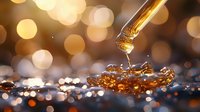 Golden liquid drops falling from glass dropper with bokeh lights background creating magical atmosphere and reflective surface with ripples.