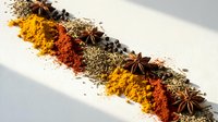 Colorful spice blend arrangement with turmeric, paprika, herbs and star anise creating aromatic cooking ingredients display for culinary recipes and food preparation.