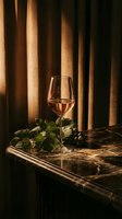 Elegant wine glass filled with white wine on marble table with fresh grapes and vine leaves against warm wooden background for luxury dining concepts.