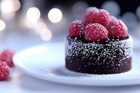 Chocolate dessert topped with fresh raspberries and powdered sugar on white plate. Blurred bokeh lights create romantic mood for food photography.