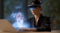 Young woman in augmented reality headset interacting with holographic hand projection while working on laptop, futuristic technology concept in dark setting.