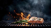 Grilled salmon fillet with rosemary on barbecue grill, flames and smoke in dark background, fresh seafood cooking outdoors for summer dining.
