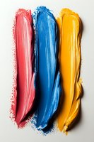 Three vibrant paint brush strokes in coral pink, blue and yellow colors on white background for creative design projects and artistic concepts.