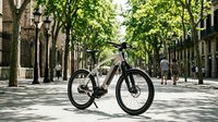 Modern electric bike parked on tree-lined urban street with pedestrians and historic buildings, suitable for cycling, transportation, and eco-friendly lifestyle content.