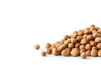 Pile of raw chickpeas scattered on white background, macro view of dried garbanzo beans. Natural protein source for vegetarian cuisine.