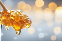 Golden honey dripping from wooden dipper with honeycomb texture against soft bokeh background, capturing sweet sticky drops in macro detail.