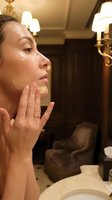 Young woman applying facial cream in elegant bathroom mirror reflection for skincare routine and beauty treatment.
