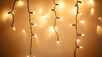 Glowing string lights hanging against warm beige background creating magical bokeh effect and festive atmosphere, suitable for holiday and celebration designs.
