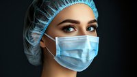 Female healthcare professional wearing surgical mask and cap, ready for medical procedures or clinical work.
