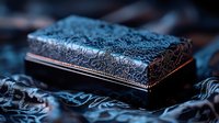 Ornate vintage jewelry box with intricate lace pattern and metallic trim captured in dramatic moody lighting with blue tones, creating mysterious atmosphere.