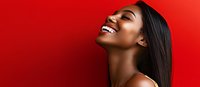 Young African American woman with straight dark hair laughing joyfully against vibrant red background, showing natural beauty and genuine happiness in profile view.