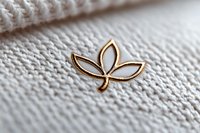 Elegant golden lotus flower pin brooch on white knitted textile background with soft focus and delicate texture. Minimalist jewelry photography.