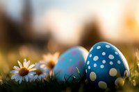 Decorated Easter eggs in blue polka dot pattern nestled in spring grass with blooming daisies at sunset, creating magical holiday atmosphere.