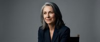 Professional mature businesswoman with gray hair in elegant black blazer smiling confidently in corporate portrait for executive leadership and business success.