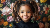 Cheerful African American girl with natural hair in pigtails smiling against floral background, wearing black blouse. Portrait captures genuine joy and innocence.