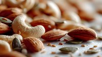 Mixed nuts and seeds collection featuring almonds cashews and pumpkin seeds scattered on rustic surface for healthy snacking and cooking ingredients.