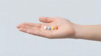 Caucasian hand holding colorful medication pills and capsules on neutral background, suitable for healthcare, pharmaceutical, wellness and medical treatment concepts.