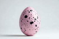 Pink speckled egg with black spots isolated on white background, resembling quail egg but in pastel color for Easter decoration or creative design.