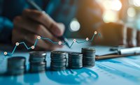 Growing stacks of coins with glowing financial chart overlay showing upward trend, business person analyzing investment data on blue background with bokeh lights.