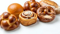 Fresh baked bread assortment with braided challah, cinnamon roll, pretzel and sesame bagel isolated on white background for bakery menu design.