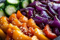 Colorful roasted vegetables including orange bell peppers, purple onions, and sliced cucumbers with sesame seeds, perfect for healthy cooking, nutrition, and food photography.