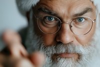 Close up portrait of mature bearded man with round glasses and piercing blue eyes looking directly at camera with intense gaze and white hair.