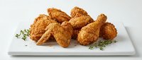 Crispy golden fried chicken pieces served on white plate with fresh herb garnish, ready for restaurant menus, food packaging, and culinary content.