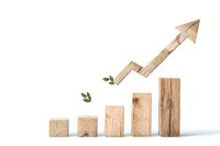 Wooden blocks arranged as ascending bar graph with arrow pointing upward and small green leaves, representing sustainable business growth and eco progress.