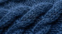 Close-up macro shot of blue knitted wool yarn texture showing detailed fiber weave patterns and soft fabric surface for crafting and textile projects.