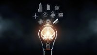 Glowing light bulb with brain inside surrounded by floating technology and business icons on dark background representing innovation and creative ideas.