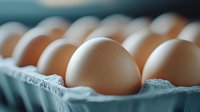 Fresh brown eggs in turquoise carton with selective focus on single egg in foreground, natural food photography with soft lighting and shallow depth of field.
