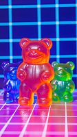 Colorful gummy bears on retro synthwave grid background with neon lighting effects. Red translucent bear in focus, blue and green bears blurred in background.