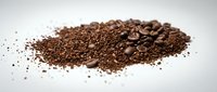 Fresh ground coffee beans and granules scattered on white surface for brewing morning espresso or filter coffee preparation in kitchen or cafe setting.