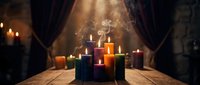 Colorful burning candles with smoke on wooden table in atmospheric candlelit room with warm lighting for relaxation meditation and spiritual practices.