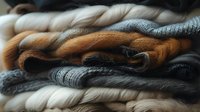 Stack of cozy knitted sweaters and scarves in neutral autumn colors creating textural layers perfect for fashion, lifestyle and seasonal content marketing.