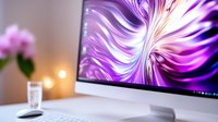 Modern workspace with computer display showing abstract purple swirl design, glass of water and blurred warm lights in background. Clean minimal desk setup.