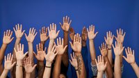 Diverse group of hands raised up against bright blue background showing unity, participation and volunteering spirit in community engagement.
