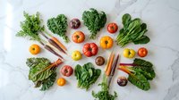 Fresh organic vegetables and colorful produce arranged on white marble surface for healthy cooking and nutrition concepts.