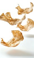 Crispy golden potato chips floating in air against white background, showcasing light and delicate texture. Isolated food photography for snack and cuisine advertising.