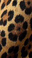 Leopard print fabric with black spots on tan and brown woven textile surface, suitable for fashion, textile design, and apparel projects.
