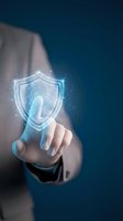 Businessman touching glowing digital shield icon representing cybersecurity protection and data safety in modern technology interface.