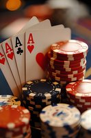 Four aces poker hand with stacked casino chips in red, blue and black colors against blurred background with warm lighting and shallow depth of field.