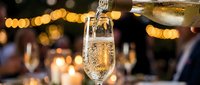 Champagne pouring into a flute glass at an elegant celebration with warm bokeh lights and festive atmosphere in the background.