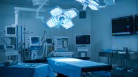 Modern operating room with surgical lights, medical equipment and monitors in sterile hospital environment for healthcare procedures and surgery operations.